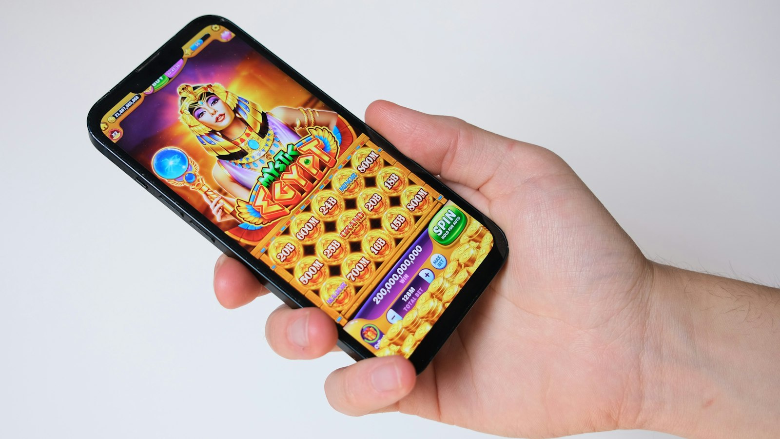 Mano sosteniendo un celular con una tragamonedas de temática egipcia en pantalla